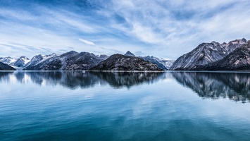 Mountains reflecting in the still waters with feathery clouds overhead